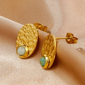 Vintage gold textured oval stud earrings with mint green gemstone on champagne satin