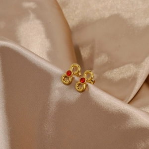 Detail of 18k gold butterfly bow stud earrings with inlaid red ruby on satin fabric
