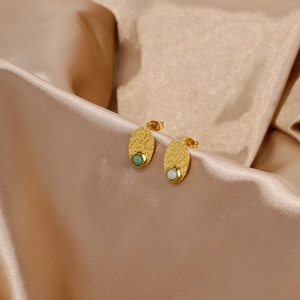 Macro view of French vintage gold earrings with textured lava finish and inlaid gemstones