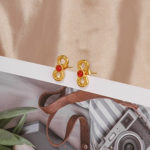 Detail of 18k gold plated infinity bow earrings with inlaid red ruby gemstones