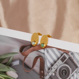 Macro view of gold hammered texture vintage earrings with turquoise stone inlay