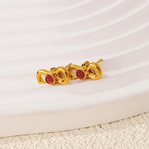 Detailed macro view of 18k gold stainless steel bow earrings with red ruby inlay