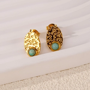 Detail of French vintage earrings with lava texture, golden finish and blue gemstones
