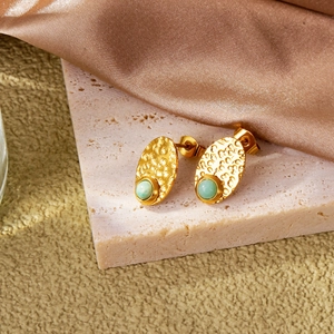 Close-up of vintage gold lava texture stud earrings with turquoise stone on silk