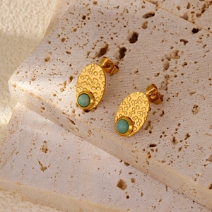 Detailed macro of vintage gold stud earrings featuring lava texture and green gemstone
