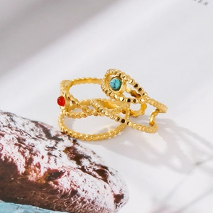 Detailed view of three stackable gold rings with turquoise and red stone insets