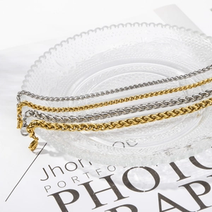 Detail of gold and silver stainless steel rope chain bracelets on a glass plate