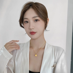 Elegante collana con pendente a moneta in acciaio inossidabile dorato su modella