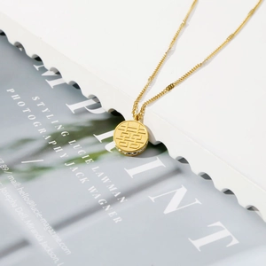 Dettaglio di una collana dorata con ciondolo rotondo 囍 e piccoli cristalli