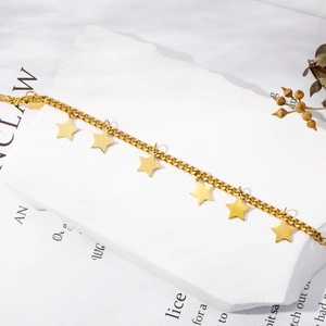 Detailed shot of a gold Cuban link chain necklace with polished star pendants on stone