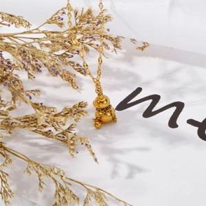 Detaillierte Nahaufnahme eines 3D-Bärenanhängers an einer Goldkette mit Blumenschatten
