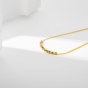 Detail of gold snake chain necklace featuring vibrant multi-color bezel-set crystals