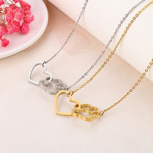 Détail macro des colliers avec pendentifs cœur et patte de chat en or et argent sur pierre