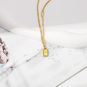 Detailaufnahme des goldenen rechteckigen Anhängers mit GOLD-Gravur auf der Kette