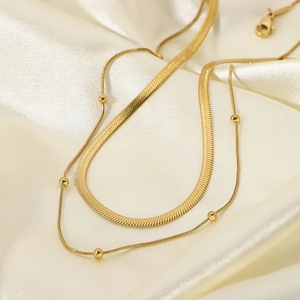 Detail of 18K gold-plated double-layer necklace with flat snake chain and bead accents