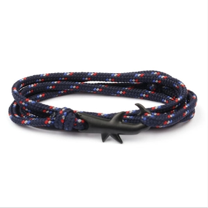 Dettaglio di un bracciale in corda intrecciata nautica con una chiusura in metallo nero opaco a forma di squalo