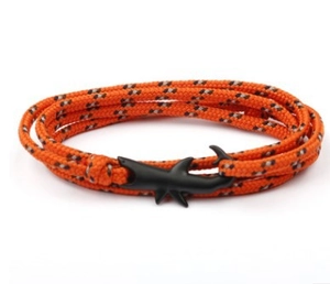 Dettaglio del bracciale multi-giro in paracord arancione con chiusura a forma di squalo