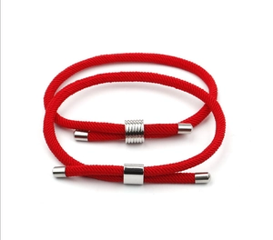 Detail of red braided cord bracelets with adjustable silver metal sliders on white background