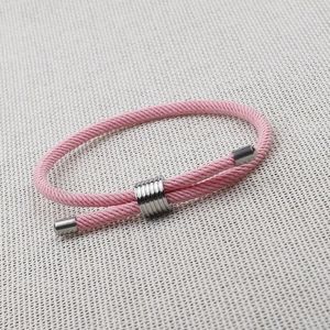 Close-up of pink woven rope bracelet featuring adjustable silver metal slider and end caps