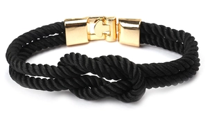 Détail d'un bracelet en corde tressée noire avec un fermoir en métal doré poli