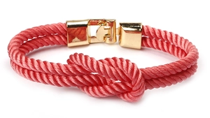 Detailed view of woven pink cord bracelet with central knot and polished gold magnetic clasp