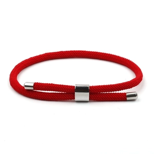 Adjustable red braided rope bracelet with polished silver metal hardware on white background