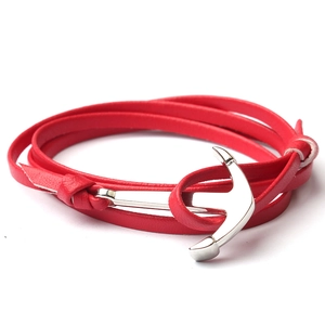 Détail d'un bracelet multicouche en cuir rouge avec un fermoir en forme d'ancre argentée