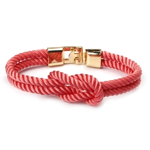 Minimalist red braided couple bracelet with golden metal clasp on white background