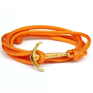 Détail d'un bracelet nautique en corde tressée orange avec fermoir ancre dorée et gravure