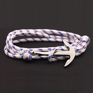 Macro detail of nautical bracelet with tri-color woven nylon cord and silver anchor clasp