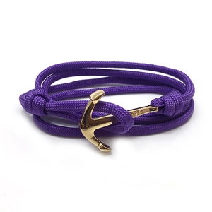 Détail d'un bracelet en paracorde violette avec un fermoir en forme d'ancre dorée polie