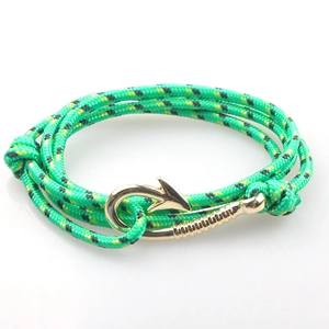 Dettaglio di bracciale in paracord verde con chiusura ad ancora a amo in metallo dorato