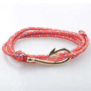 Dettaglio del bracciale nautico in corda intrecciata arancione con chiusura a amo dorata