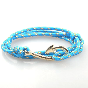 Vista macro del bracciale in corda nautica blu intrecciata con chiusura a amo dorata