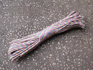 Detailed view of rainbow woven 7-strand paracord with spiral texture on grey surface