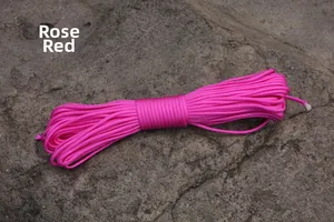 Detail view of durable rose red 100m paracord roll on natural grey rock background