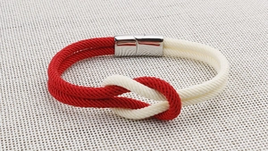 Detailaufnahme des rot-weißen geflochtenen Armbands mit silbernem Magnetverschluss