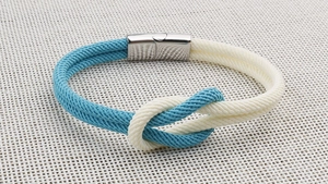 Makroaufnahme eines nautischen Seilarmbands mit Seemannsknoten und silbernem Magnetverschluss