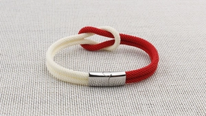 Detailansicht des Seemannsknotens am rot-weißen geflochtenen Armband mit Metallverschluss