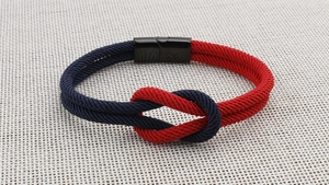 Detail eines Segelknoten Armbands in Marineblau und Rot mit schwarzem Magnetverschluss