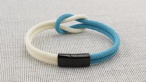 Makroaufnahme des zweifarbigen geflochtenen Armbands mit schwarzem Magnetverschluss