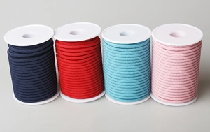 Detailansicht von geflochtenen Nylonschnüren in Marine, Rot, Blau und Rosa auf Spulen