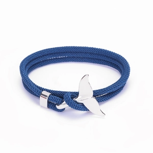 Dettaglio di un bracciale intrecciato blu navy con ciondolo a forma di coda di balena
