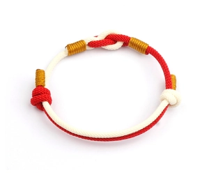 Close-up of hand-woven red and white rope bracelet with golden metallic wire details