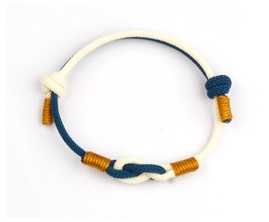 Detail of adjustable hand-woven couple bracelet with deep blue and cream silk cords
