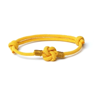 Detail of adjustable bright yellow woven bracelet with intricate golden thread accents