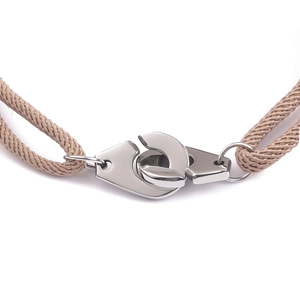 Macro view of polished stainless steel handcuff clasp with woven cord bracelet