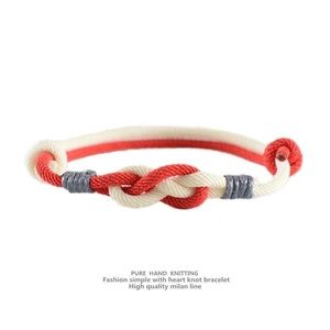 Detail of hand-knitted heart knot couple bracelet made of red and white milan line