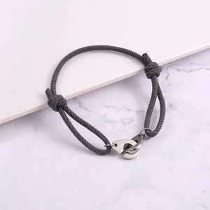 Macro shot of grey braided rope bracelet with polished silver metal handcuff clasp