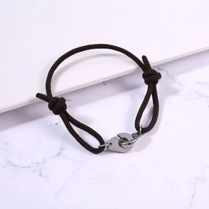 Detail of adjustable dark brown braided rope bracelet with silver handcuff metal clasp